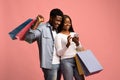 Happy black man and woman holding shopping bags, using smartphone Royalty Free Stock Photo