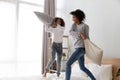 Happy black mom and daughter have pillow fight on bed