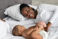 Happy black mom lying in bed with her cute infant Royalty Free Stock Photo