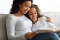 Happy black mother and daughter reading book together