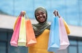 Happy black muslim woman with lots of shopping bags posing outdoors