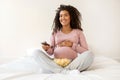 Happy Black Pregnant Lady Relaxing At Home, Watching Tv And Eating Popcorn Royalty Free Stock Photo