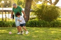 Happy black small boy and european old man with beard play at ball, at football in park, outdoor Royalty Free Stock Photo