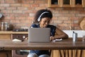 Happy Black student girl in wireless headphones writing notes