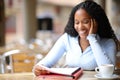 Happy black student memorizing notes in a coffee shop