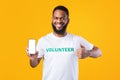 Happy Black Volunteer Showing Phone Screen Gesturing Thumbs-Up, Yellow Background