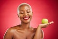 Happy black woman, apple and natural nutrition for healthy diet against a red studio background. African female person Royalty Free Stock Photo