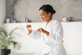 Happy black woman in bathrobe preparing to brush her teeth, applying toothpaste Royalty Free Stock Photo