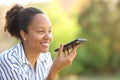 Happy black woman dictating message on cell phone Royalty Free Stock Photo