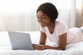 Happy black woman flirting online on laptop in bed Royalty Free Stock Photo