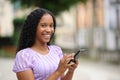 Happy black woman holding cell phone looks at you Royalty Free Stock Photo