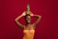 Happy black woman holding pineapple on head and laughing Royalty Free Stock Photo