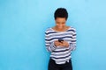 Happy black woman looking at mobile phone by blue background Royalty Free Stock Photo