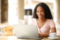 Happy black woman looking at you using laptop in a restaurant Royalty Free Stock Photo