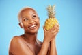 Happy black woman, pineapple and thinking for diet or natural nutrition against a blue studio background. Thoughtful