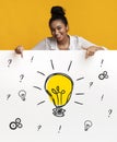 Happy black woman pointing at banner with drawing of light bulb, gears and question marks Royalty Free Stock Photo