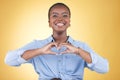 Happy black woman, portrait and heart hands for support, love or care against a yellow studio background. Face of Royalty Free Stock Photo