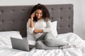 Happy black woman sitting on bed talking on phone Royalty Free Stock Photo