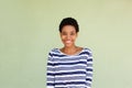 Happy black woman in striped shirt smiling by green background
