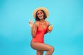 Happy black woman in swimsuit enjoying exotic summer cocktail and showing peace sign, posing over blue background Royalty Free Stock Photo