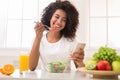 Happy black woman texting on smartphone while eating salad Royalty Free Stock Photo