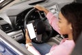 Happy black woman using smartphone with empty screen driving car