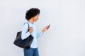 Happy black woman walking with mobile phone and purse on gray background Royalty Free Stock Photo