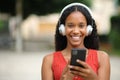 Happy black woman wearing headphone holding phone Royalty Free Stock Photo