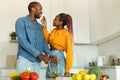 Happy black woman feeding her husband, couple preparing healthy lunch in light kitchen interior, free space Royalty Free Stock Photo