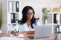 Happy black young business lady working on laptop at office, taking notes during online work meeting or webinar Royalty Free Stock Photo