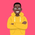 A happy black young guy in glasses stands with his arms crossed. African successful confident boy in yellow hoodie