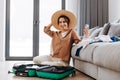 Happy blogger girl with a hat shows her followers how she is packing her suitcase for vacation. Relaxation concept Royalty Free Stock Photo