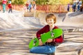 Happy blond boy with green skateboard sitting Royalty Free Stock Photo