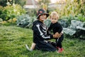 A happy blond boy and his sister in carnival skeleton costumes are playing in the garden on Halloween eve