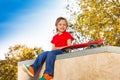 Happy blond boy sitting with skateboard alone Royalty Free Stock Photo