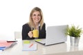 Happy blond business woman working on computer laptop with coffee cup Royalty Free Stock Photo