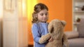 Happy blond curly-haired little girl playing with favorite teddy bear, childhood Royalty Free Stock Photo