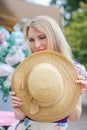 Happy blond girl with a straw hat screwing up her right eye smiling
