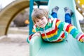 Happy blond kid boy having fun and sliding on outdoor playground Royalty Free Stock Photo