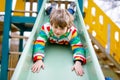 Happy blond kid boy having fun and sliding on outdoor playground Royalty Free Stock Photo