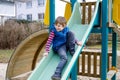 Happy blond kid boy having fun and sliding on outdoor playground Royalty Free Stock Photo