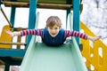 Happy blond kid boy having fun and sliding on outdoor playground Royalty Free Stock Photo