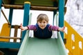 Happy blond kid boy having fun and sliding on outdoor playground Royalty Free Stock Photo