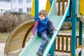 Happy blond kid boy having fun and sliding on outdoor playground Royalty Free Stock Photo