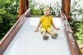 Happy blond kid boy having fun and sliding on outdoor playground. Summer leisure for kids Royalty Free Stock Photo