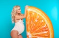 Happy blond pregnant woman expecting maternity with her belly by orange inflatable mattress isolated on studio blue background. Royalty Free Stock Photo