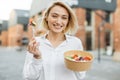 Happy blond smiling woman freelancer, manager, business lady, eating fresh vegetable salad Royalty Free Stock Photo