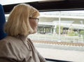 Happy blond woman with glasses, looks out the window of the train, trip, journey