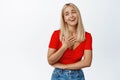 Happy blond woman laughing, smiling and looking thankful, pleased with something, standing against white background