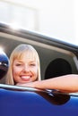 Happy blond woman sitting at the window seat of a car. Portrait of a smiling blond female sitting relaxed at the window Royalty Free Stock Photo